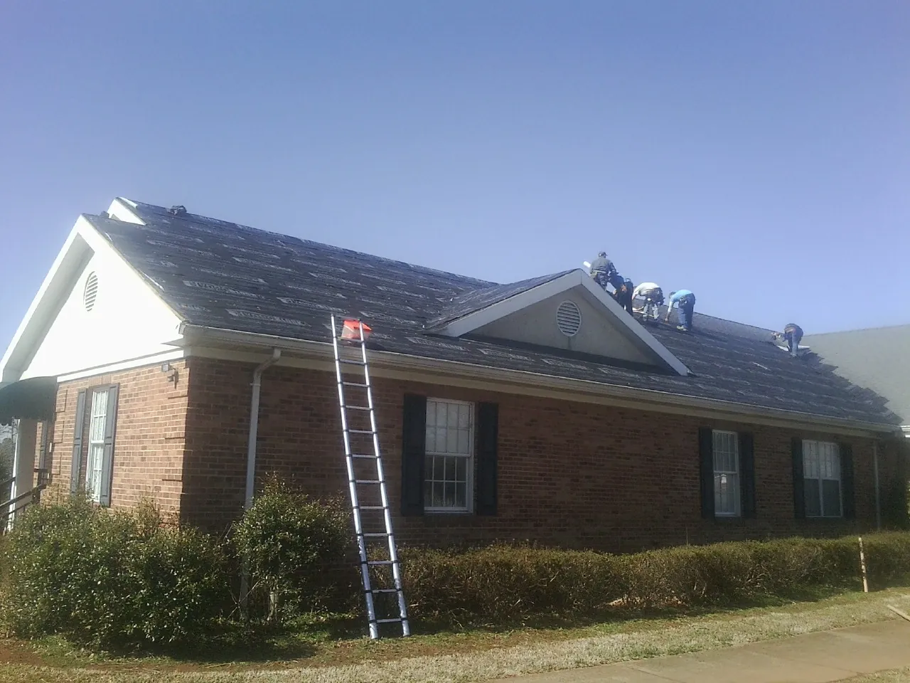 Crew tearing shingles off a brick ranch roof with a ladder set — Metal Roof Repair work by our crew in Guatay
