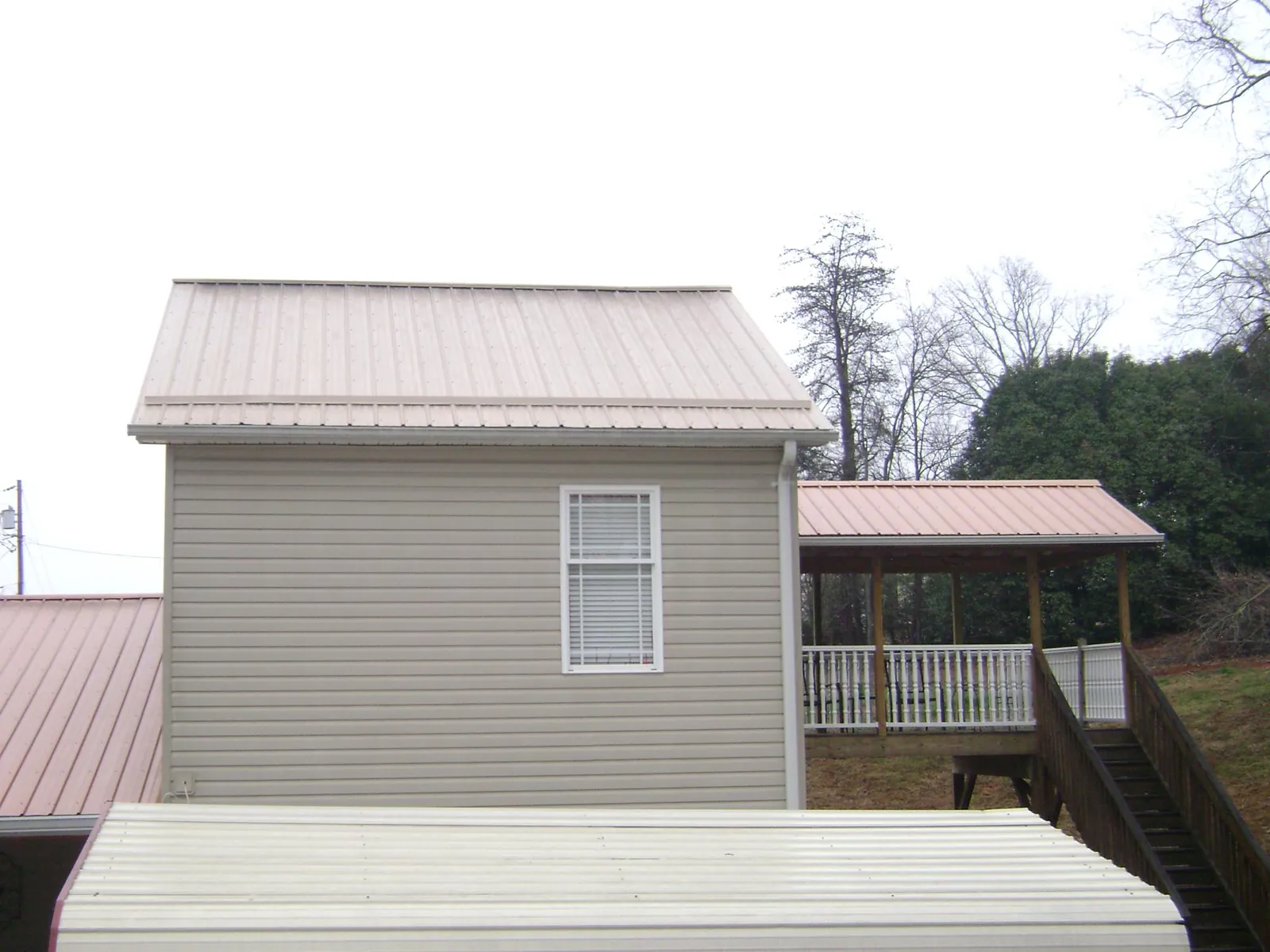 Tan metal roofs on a two story addition and attached porch, from a Roof Replacement job in Guatay