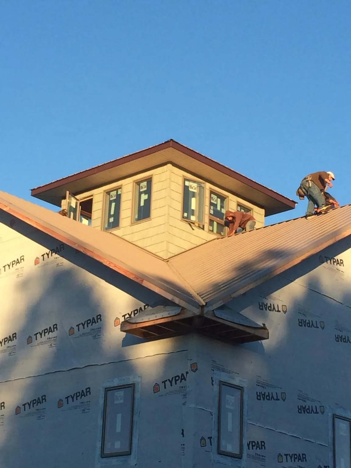 Roofers working around a rooftop cupola on a new metal roof at sunset — Roof Waterproofing in Guatay by Roofing Brothers